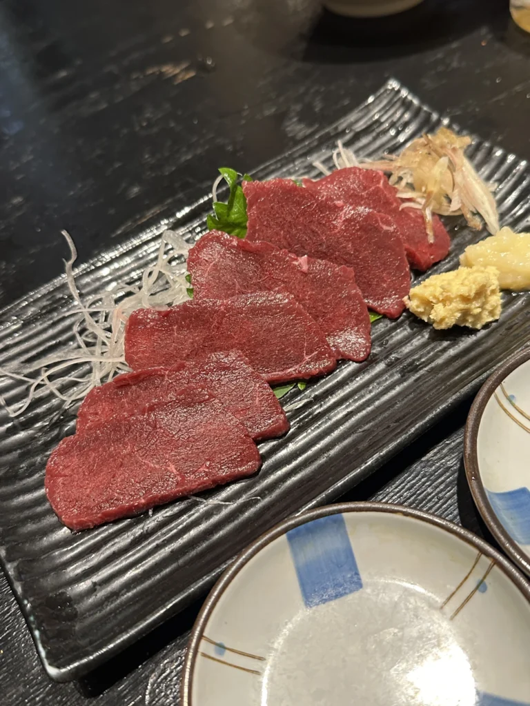 赤身の馬刺しと薬味が並ぶ皿