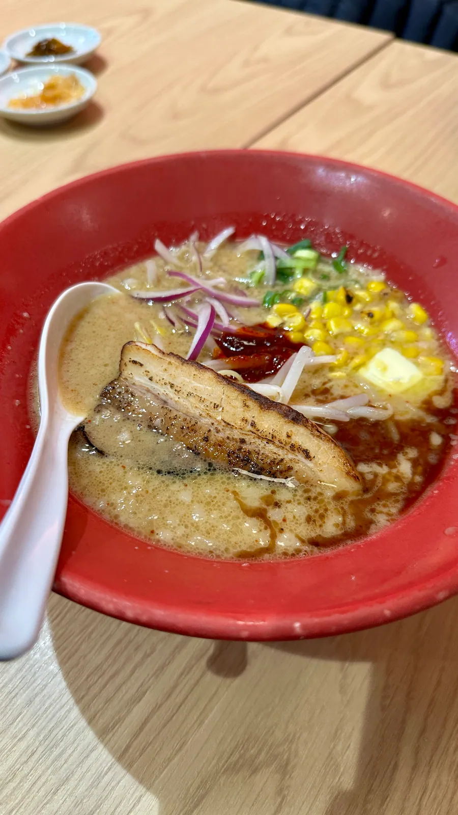 炙りチャーシュー、ネギ、レッドオニオンを盛り付けた味噌豚骨ラーメンの味噌赤丸